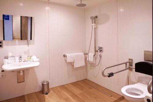 a bathroom with a shower and a sink and a toilet at Hilton Garden Inn Munich Messe in Feldkirchen
