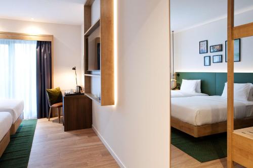 a hotel room with two beds and a mirror at Hilton Garden Inn Munich Messe in Feldkirchen