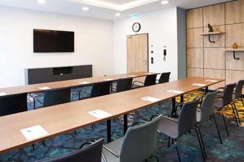 a conference room with tables and chairs and a tv at Hilton Garden Inn Munich Messe in Feldkirchen