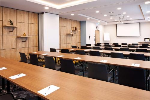a conference room with tables and chairs and a screen at Hilton Garden Inn Munich Messe in Feldkirchen