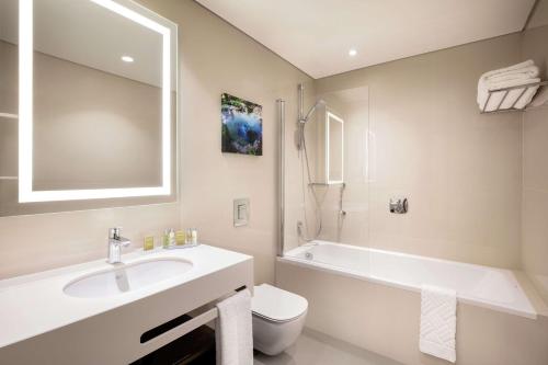 La salle de bains est pourvue d'un lavabo, d'une baignoire et de toilettes. dans l'établissement Hilton Garden Inn Tirana, à Tirana
