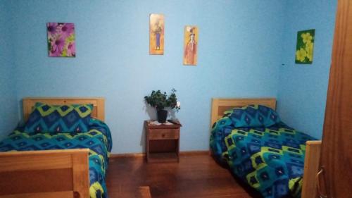 a bedroom with two beds and a table and pictures on the wall at Hostel Chango in Caldera