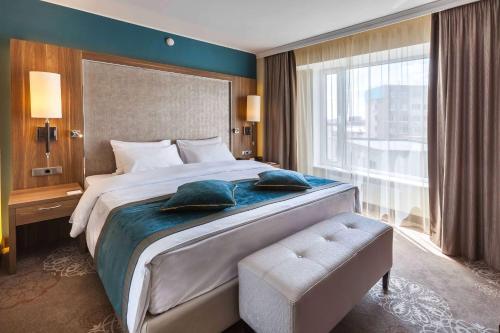 a bedroom with a large bed and a large window at DoubleTree by Hilton Hotel Tyumen in Tyumen