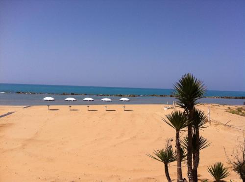 a beach with several chairs and umbrellas on it at Hotel Costazzurra Museum & Spa in San Leone