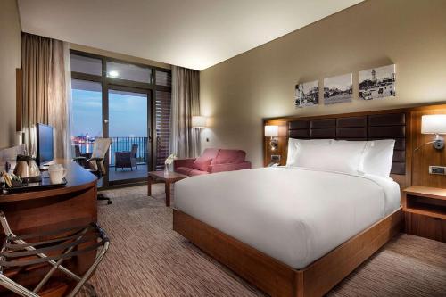 a bedroom with a large bed and a living room at Hilton Garden Inn Izmir Bayrakli in Izmir