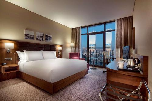 a hotel room with a bed and a large window at Hilton Garden Inn Izmir Bayrakli in Izmir