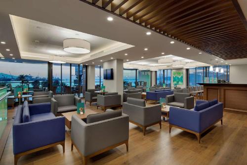 a restaurant with blue chairs and tables and windows at Hilton Garden Inn Izmir Bayrakli in Izmir