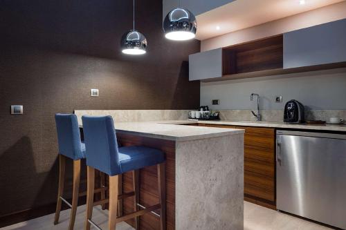 a kitchen with two blue bar stools at a counter at Hilton Garden Inn Izmir Bayrakli in Izmir