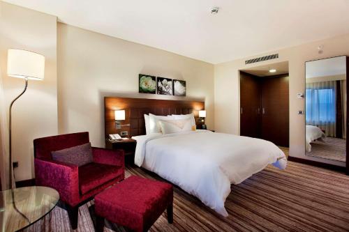 a hotel room with a large bed and a chair at Hilton Garden Inn Sanliurfa in Urfa