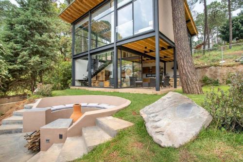 a large glass house with a bench in the yard at CASA NUEVA en Avandaro rodeada de Naturaleza in Valle de Bravo