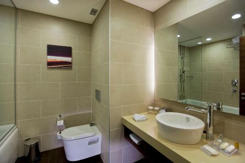 Un baño con lavabo, inodoro y espejo. en Hilton Garden Inn Kutahya, en Kütahya