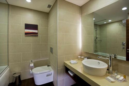 a bathroom with a sink and a toilet and a mirror at Hilton Garden Inn Kutahya in Kütahya
