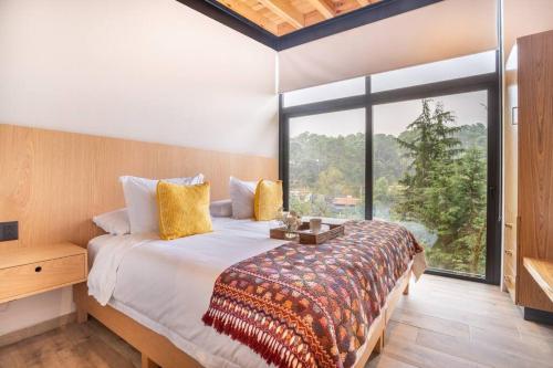 ein Schlafzimmer mit einem Bett und einem großen Fenster in der Unterkunft CASA NUEVA en Avandaro rodeada de Naturaleza in Valle de Bravo