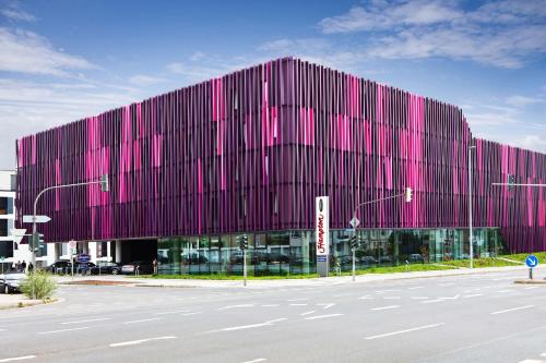 un grand bâtiment avec une façade rose dans une rue dans l'établissement Hampton By Hilton Aachen Tivoli, à Aix-la-Chapelle