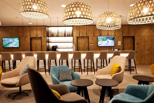 a lobby with chairs and a bar with televisions at Hampton By Hilton Aachen Tivoli in Aachen