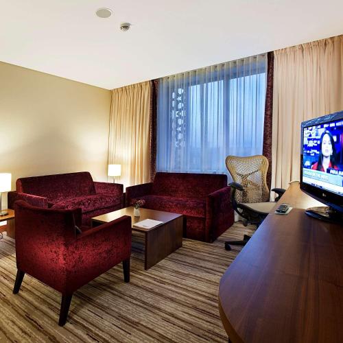 a hotel room with red furniture and a flat screen tv at Hilton Garden Inn Konya in Konya