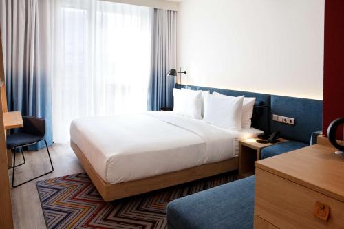 a hotel room with a bed and a window at Hampton by Hilton Munich Airport South in Hallbergmoos