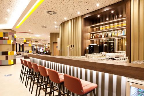 una fila di sedie al bar di un ristorante di Hampton by Hilton Munich Airport South a Hallbergmoos