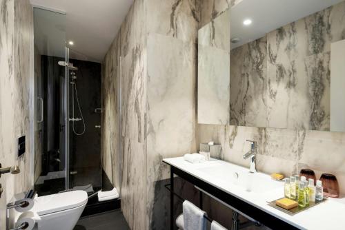 a bathroom with a sink and a toilet and a shower at DoubleTree by Hilton Madrid-Prado in Madrid