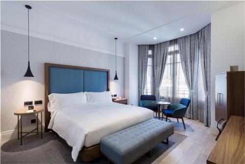 Habitación de hotel con cama, mesa y sillas en DoubleTree by Hilton Madrid-Prado, en Madrid