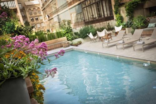 a swimming pool with chairs and flowers on a building at Alexandra Barcelona Hotel, Curio Collection by Hilton in Barcelona