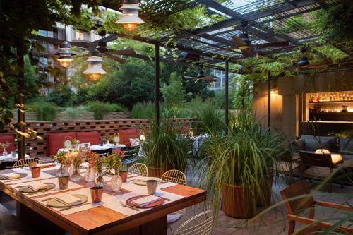a restaurant with a long table with plants in a patio at Alexandra Barcelona Hotel, Curio Collection by Hilton in Barcelona