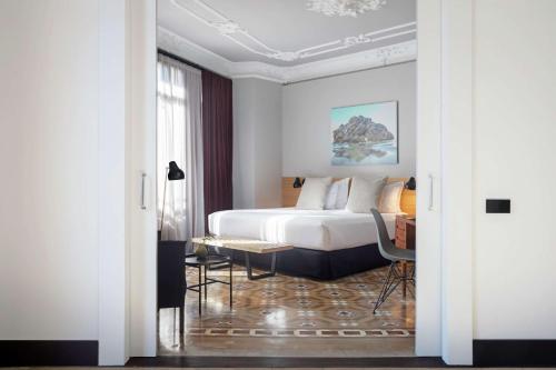 a hotel room with a bed and a desk at Alexandra Barcelona Hotel, Curio Collection by Hilton in Barcelona