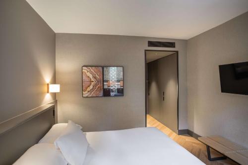 a bedroom with a white bed and a picture on the wall at Alexandra Barcelona Hotel, Curio Collection by Hilton in Barcelona