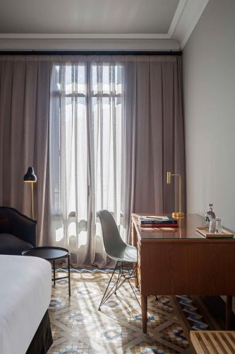a hotel room with a desk and a bed and a window at Alexandra Barcelona Hotel, Curio Collection by Hilton in Barcelona