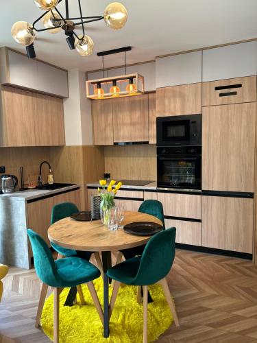 cocina con mesa de madera y sillas verdes en Apartament Perła Kutna, en Kutno