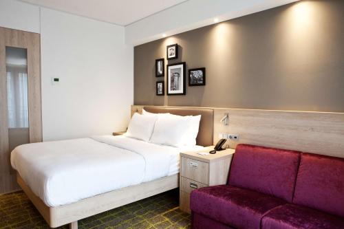 a hotel room with a bed and a couch at Hampton By Hilton Dortmund Phoenix See in Dortmund