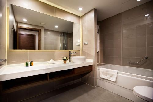 a bathroom with a sink and a tub and a mirror at Hilton Garden Inn Erzincan in Erzincan