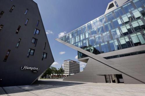a large glass building next to a tall building at Hampton By Hilton Olsztyn in Olsztyn