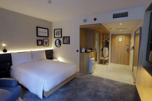 a bedroom with a white bed and a blue couch at Hampton By Hilton Olsztyn in Olsztyn
