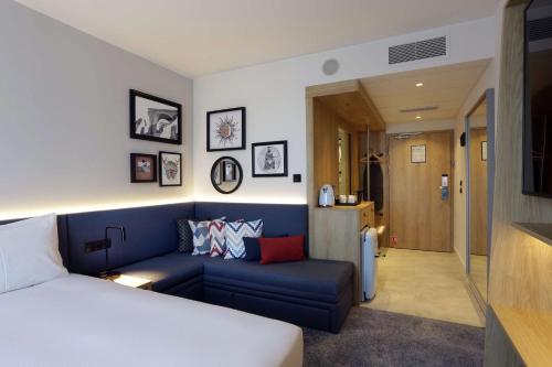 sypialnia z niebieską kanapą i łóżkiem w obiekcie Hampton By Hilton Olsztyn w Olsztynie