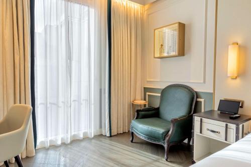 a hotel room with a green chair and a window at The Emerald House Lisbon - Curio Collection By Hilton in Lisbon