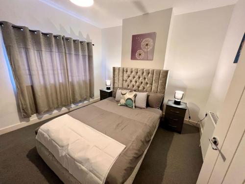 um quarto com uma cama grande e 2 mesas de cabeceira em 4 Bedroom Terrace house em Wellingborough