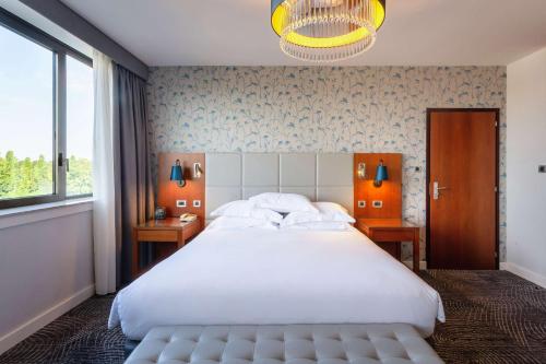 Un dormitorio con una gran cama blanca y una lámpara de araña. en Hilton Strasbourg, en Estrasburgo