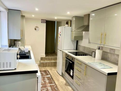 a kitchen with white cabinets and a white refrigerator at 4 Bedroom Terrace house in Wellingborough
