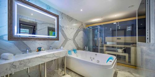 a bathroom with a tub and a sink and a mirror at Hilton Podgorica Crna Gora in Podgorica