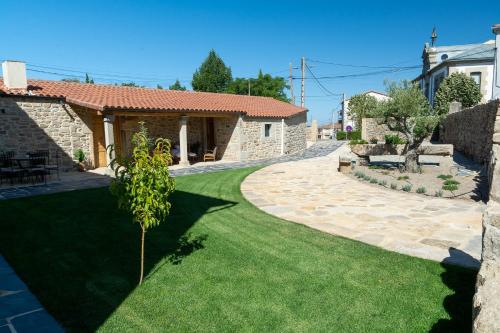 a garden with a stone house and a lawn at LA ALCOBA DE SAYAGO in Bermillo de Sayago