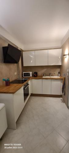 une cuisine avec des armoires blanches et un évier dans l'établissement Villa Ange Azur, à Villeneuve-Loubet