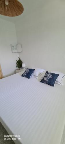 un letto bianco con due cuscini blu sopra di Villa Ange Azur a Villeneuve-Loubet