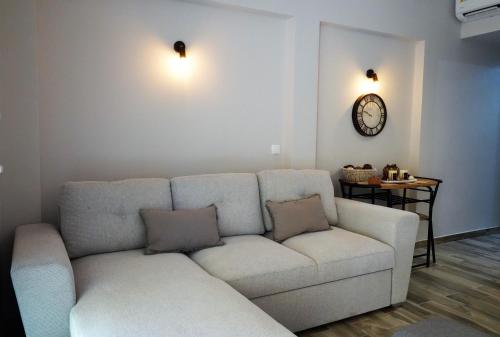 a living room with a couch and a clock on the wall at Ζωή Apartment in Preveza