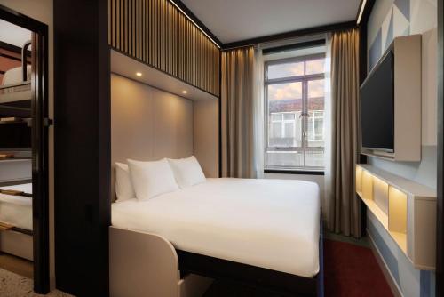 a bedroom with a white bed and a window at Motto By Hilton Rotterdam Blaak in Rotterdam