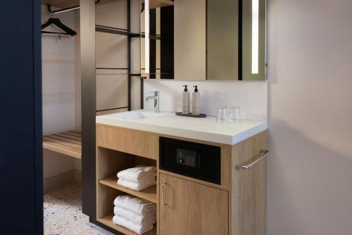 a bathroom with a sink and a mirror and towels at Motto By Hilton Rotterdam Blaak in Rotterdam