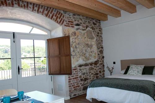 a bedroom with a bed and a brick wall at El Esquileo in Buitrago del Lozoya