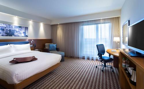 a hotel room with a bed and a desk and a television at Hampton by Hilton Gdansk Airport in Gdańsk-Rębiechowo
