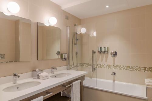 a bathroom with two sinks and a shower and a tub at Hampton By Hilton Rome East in Rome