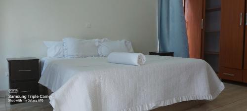 a white bed with a white blanket and pillows at HARRIET APARTHOTEL Kigali-NYARUTARAMA in Kigali